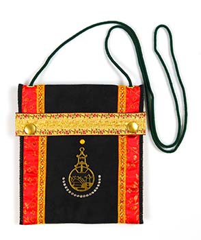 Alcantarastof met messing-symbool en goud en roodkleurig band. Het lijkt op een tempeltasje. Sluiting bestaat uit twee drukknopen. Zwart koord als schouderband.