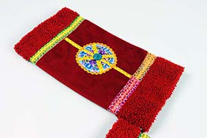 Alcantara stof bewerkt met bloemapplicatie en knoop. Verschillende soorten band. Ritssluiting.
